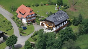 Une maison à deux étages avec un toit rouge, un garage et une installation de panneaux solaires.