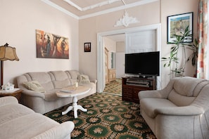A living room with a sofa, a coffee table, a television, and a patterned carpet.