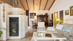 A cozy living room with a fireplace, a sofa, a table with candles, and a dining area with chairs.