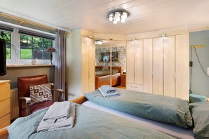 Un dormitorio con cama, una silla, un armario y una televisión.
