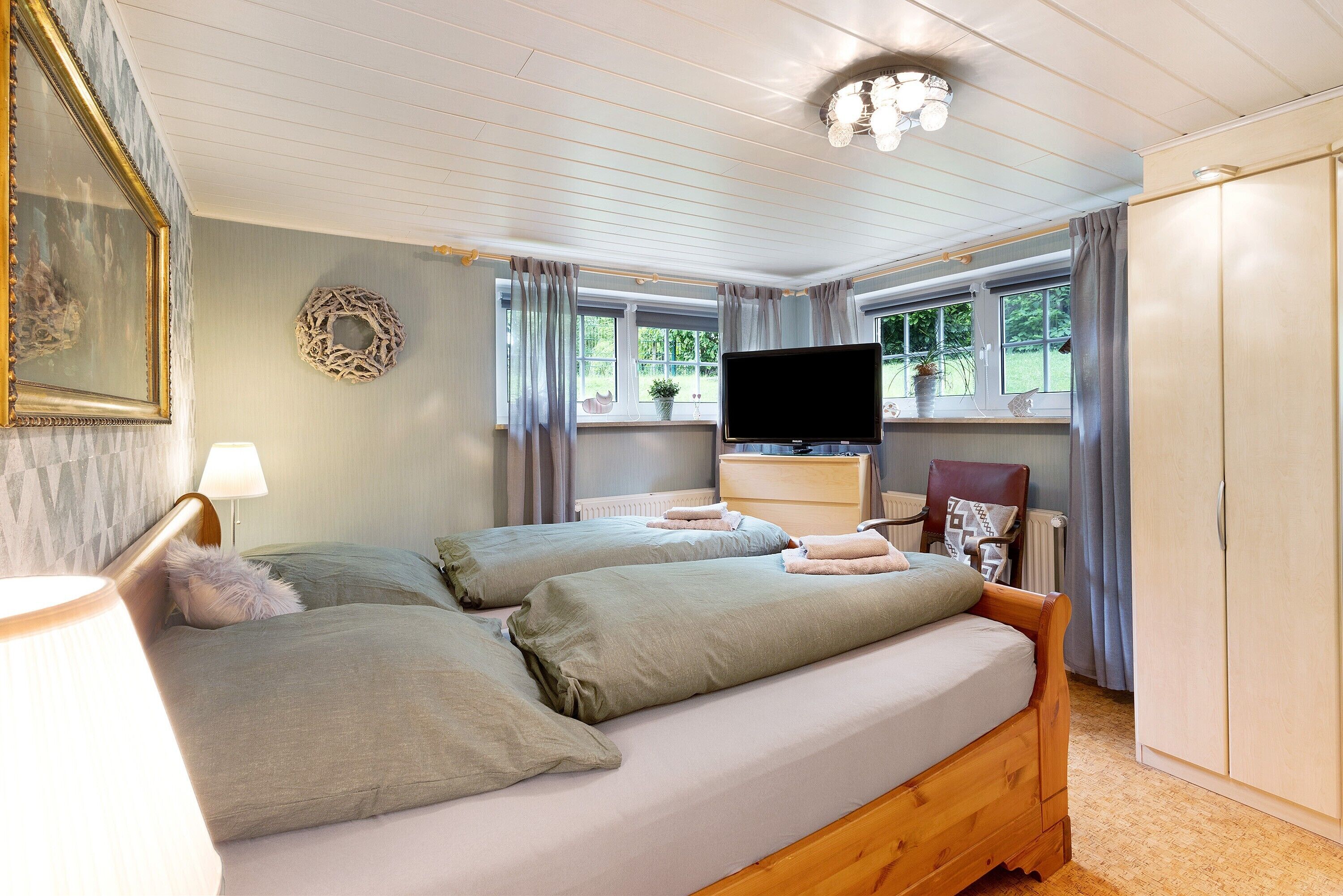 A bedroom with two beds, a TV, a dresser, and a wardrobe.
