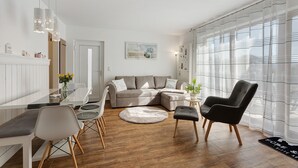 A modern living room with a sectional sofa, a dining table, and a black armchair.