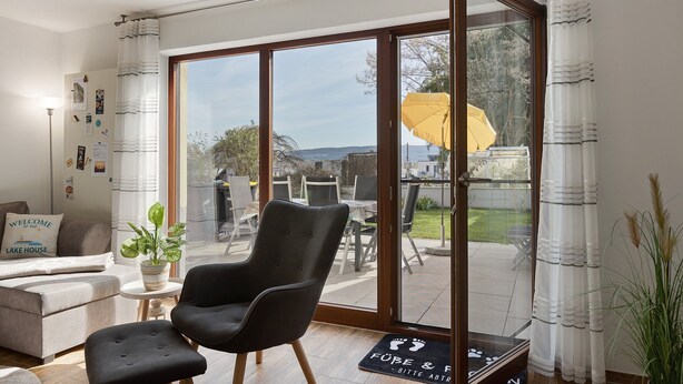 A modern living room with a sofa, a black armchair, a coffee table, and a potted plant.