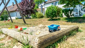 Un bac à sable avec des jouets et une balançoire dans un quartier résidentiel.