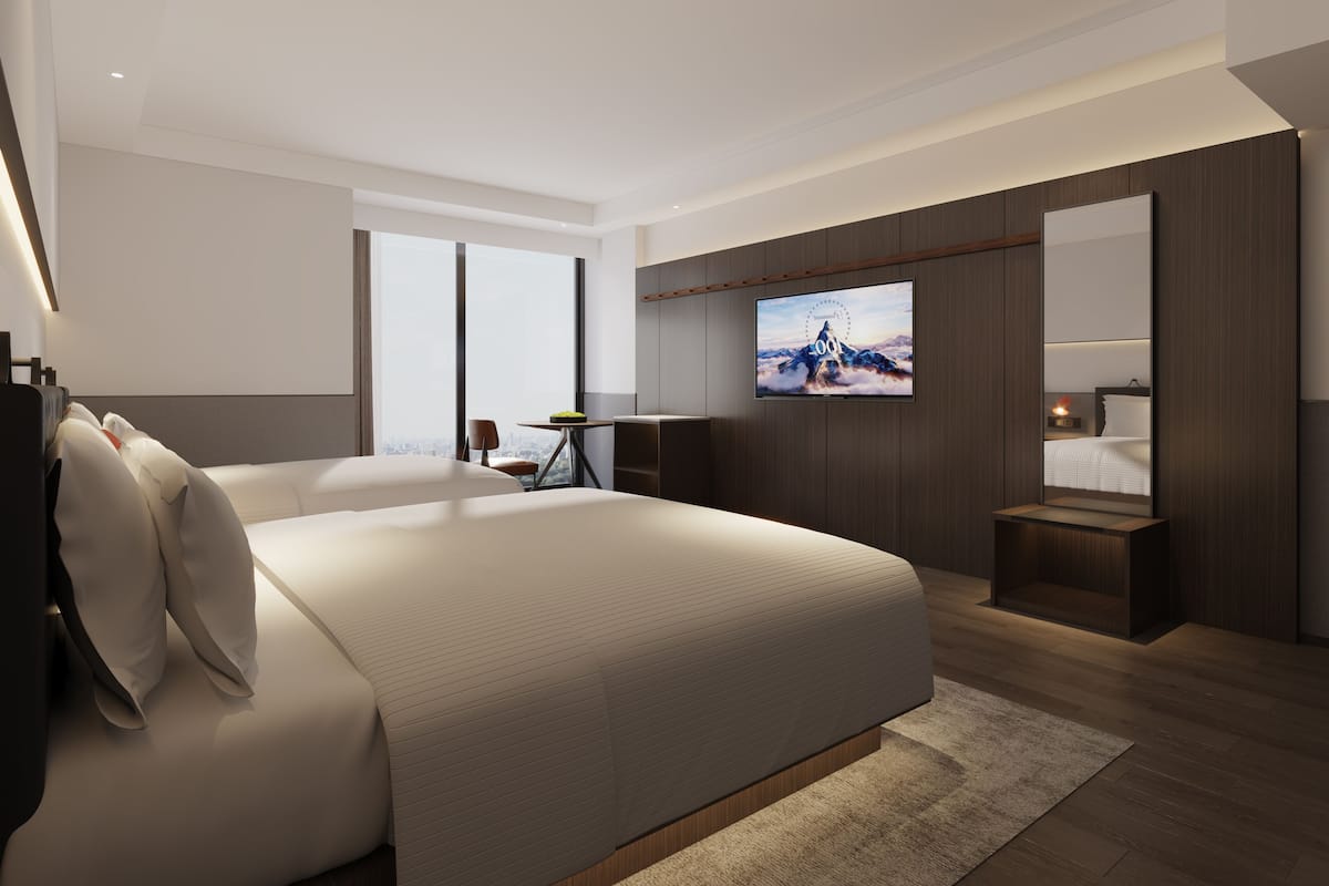 A modern hotel room with a large bed, a desk, a TV, and a mirror.