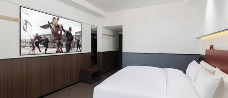 Une chambre d’hôtel dotée d’un grand lit, d’un téléviseur à écran plat fixé au mur, de panneaux décoratifs en bois et d’un petit coin salon.