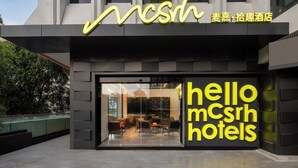 A modern hotel entrance with a glass facade, interior seating visible, and a prominent 'hello mcsrh hotels' sign. - Mcsrh Hotel -Chengdu Jiuyanqiao (Chengdu)