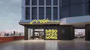A modern hotel with a cityscape view, featuring a prominent 'hello mcsrh hotels' sign and a seating area with chairs and tables. - Mcsrh Hotel -Chengdu Jiuyanqiao (Chengdu)
