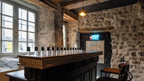 Un espace bar avec un comptoir en bois, des murs en pierre et un panneau lumineux au néon.