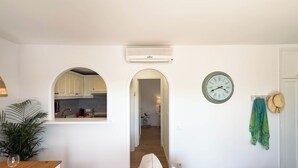 Una sala de estar con un sofá, una mesa de comedor y una cocina visible a través de un arco.