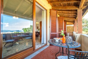 A terrace with a table and chairs, a view of the outdoors, and a door leading to an interior space. - Sardinia Re - Villino Silvia (Alghero)