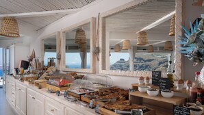 A breakfast buffet with various food items and a view of the mountains. - Two-Bedroom Caldera View (Thira - Santorini)