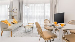 Una sala de estar moderna con sofá, mesa de comedor, sillas y televisor.