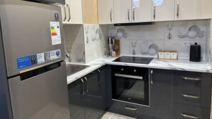 Moderni keittiö, jossa on ruostumattomasta teräksestä valmistetut kodinkoneet, Bosch-uuni ja digitaalinen jääkaappi.
