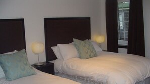 Una camera d'albergo con due letti singoli, ciascuno dotato di poggiatesta, comodino e lampada.