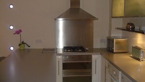 Una cucina moderna con cappa in acciaio inossidabile, forno integrato e microonde.
