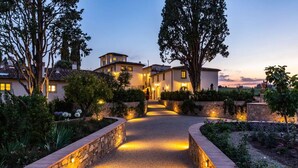 Un sendero bien iluminado que conduce a una hilera de casas con paredes de piedra y un jardín lleno de flores.