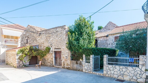 A stone building with a wooden door and a bench outside.