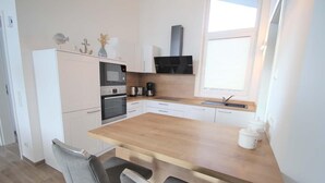 A modern kitchen with a wooden island, white cabinetry, and a built-in oven.