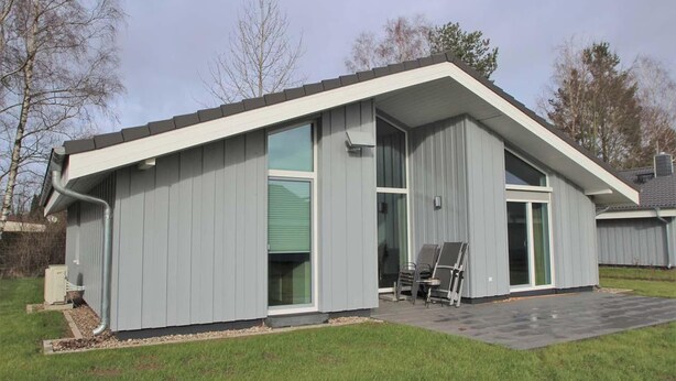 A modern building with a flat roof, large windows, and a covered patio area.