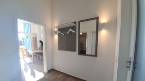 Ein Flur mit Holzboden, einer Tür rechts und einem Spiegel an der Wand.