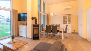 Eine moderne Küche mit Einbauherd, Essbereich mit Stühlen und ein großes Fenster mit Blick ins Freie.