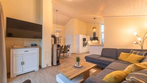 Ein modernes Wohnzimmer mit grauem Sofa, einem Couchtisch und einem Essbereich mit Tisch und Stühlen.