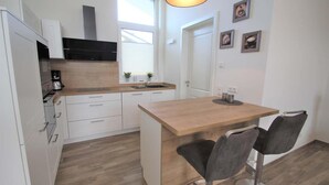 Una cocina compacta con armarios blancos, encimera de madera y una pequeña isla con dos taburetes de bar.