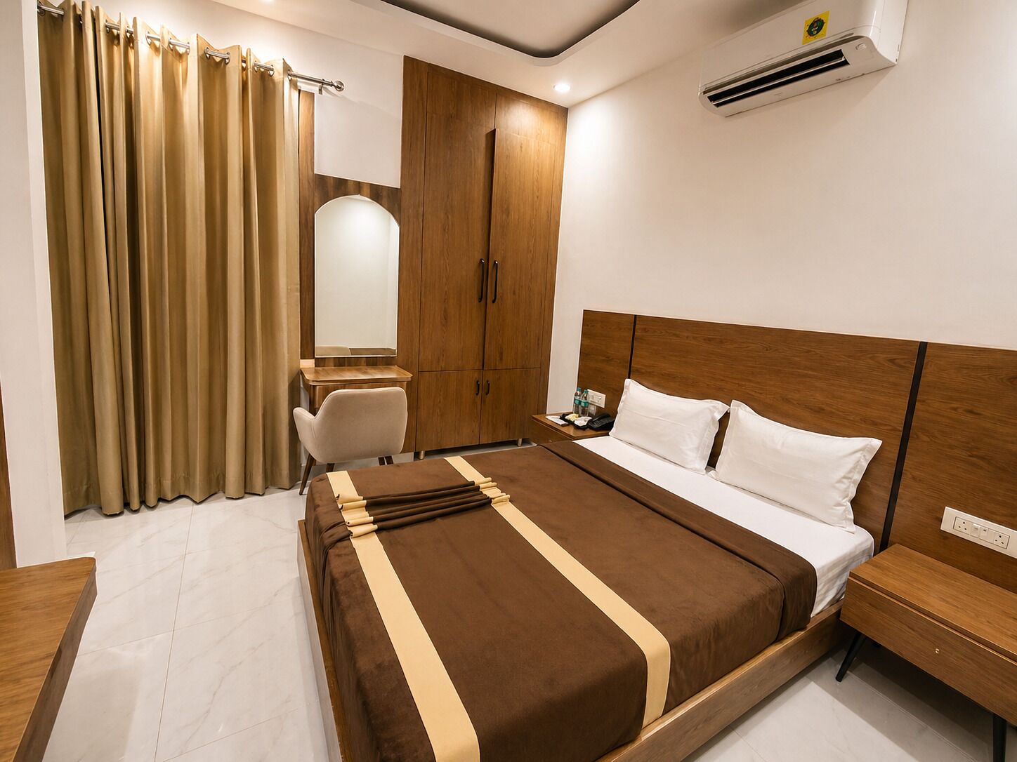 Camera d'albergo con un letto, comodino, scrittoio, sedia, armadio e tende.