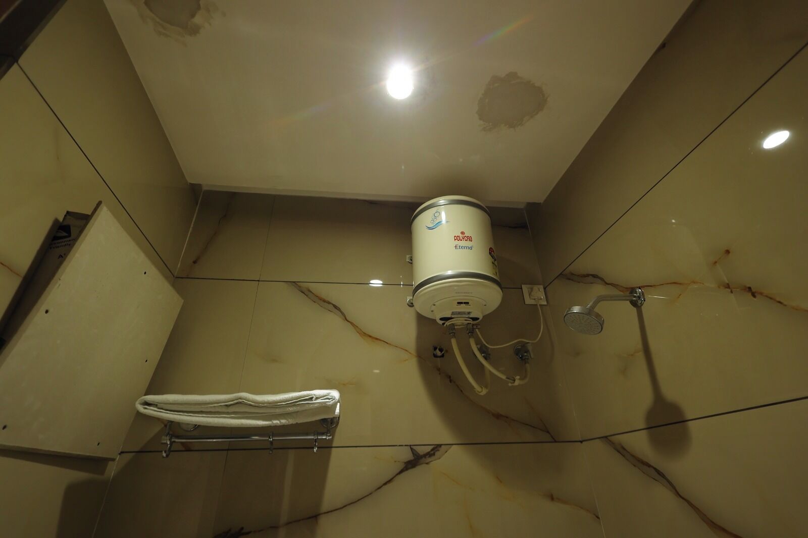 A bathroom with a white toilet, a towel rack, and a water heater mounted on the wall.