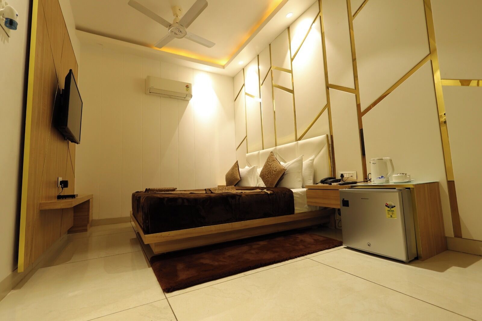 A modern bedroom with a bed, bedside table, and a small refrigerator.