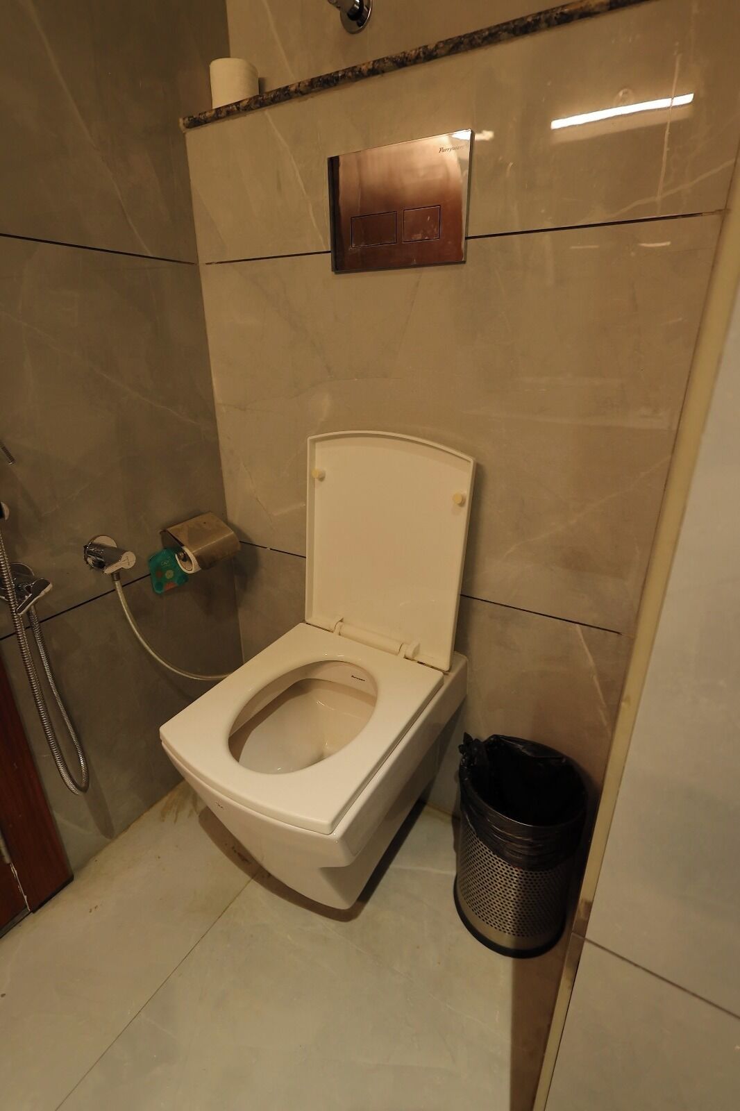 Ein Badezimmer mit Toilette, Handtrockner und Mülleimer.