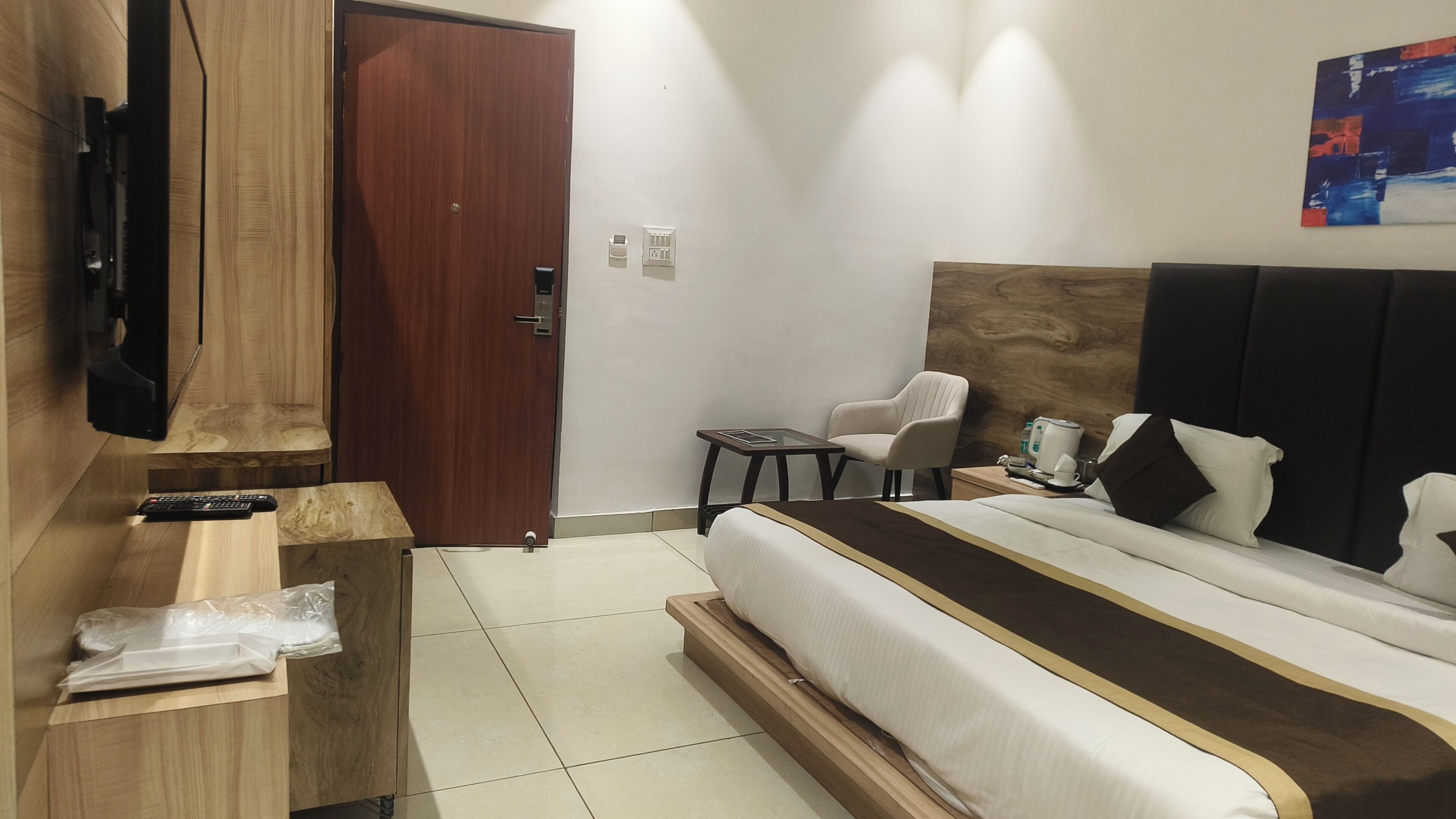 Una camera d'albergo con un letto, una TV, una scrivania, una sedia e una porta.