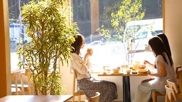 Enjoy meals in this dining area with a large potted plant and natural light pouring in from the large windows.