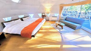 Habitación amplia con una cama grande, un sofá y una mesita. Cuenta con una ventana que proporciona luz natural y vistas al exterior.