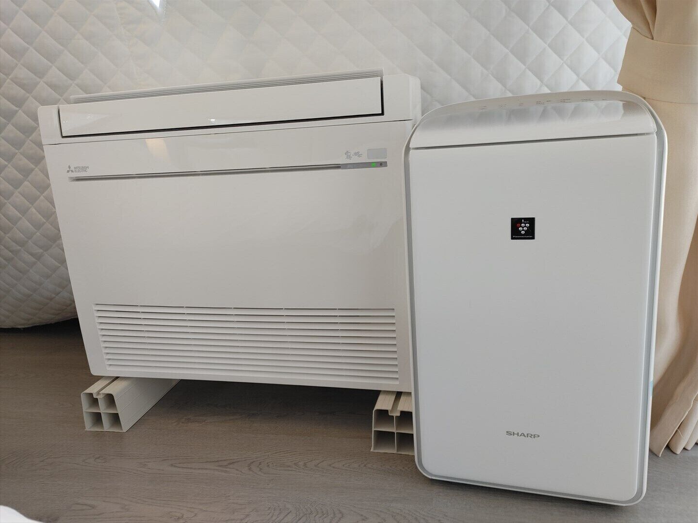 A white portable air conditioner with a control panel and a smaller unit beside it.