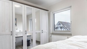 Een slaapkamer met een groot raam, een bed en een garderobe met spiegeldeuren.