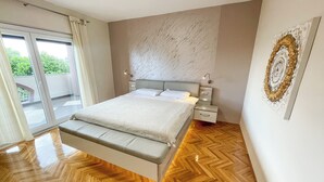 Egy hálószoba, amelyben található egy ágy, éjjeliszekrények, márványból készült fal és fa padló.
