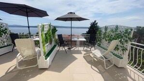 Una terraza con mobiliario exterior, vista al mar y una cerca blanca de celosía.