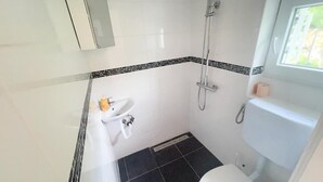 Un baño pequeño con inodoro, lavabo y ducha.