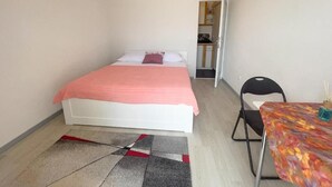 Un dormitorio con cama, una silla, una mesa y una puerta que da a un baño.