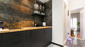 A modern kitchen with dark cabinetry, a wooden countertop, and a rustic wall. - Luxury 5 by OTOTO (Thessaloniki)