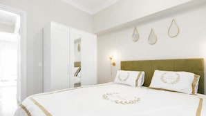 A hotel room with a large bed, a wardrobe, and a wall-mounted light fixture. - Luxury 5 by OTOTO (Thessaloniki)