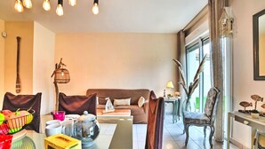 Un salon moderne avec un canapé, une table à manger et des chaises, ainsi qu’une grande fenêtre avec des rideaux.