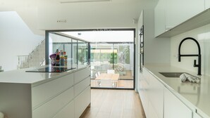 A modern kitchen with a glass door leading to a dining area, white cabinetry, and a black faucet.