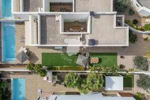 Ein modernes, zweistöckiges Haus mit Swimmingpool, Terrasse und Gartenmöbeln sowie einem gepflegten Garten.