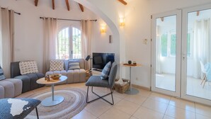 Una sala de estar con sofá, sillón, televisor y una mesita con un tazón.