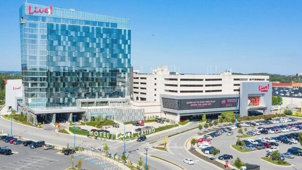 A hotel with a modern glass facade and a casino sign. - Cozy Retreat Near Fort Meade | Fire Pit (Severn)