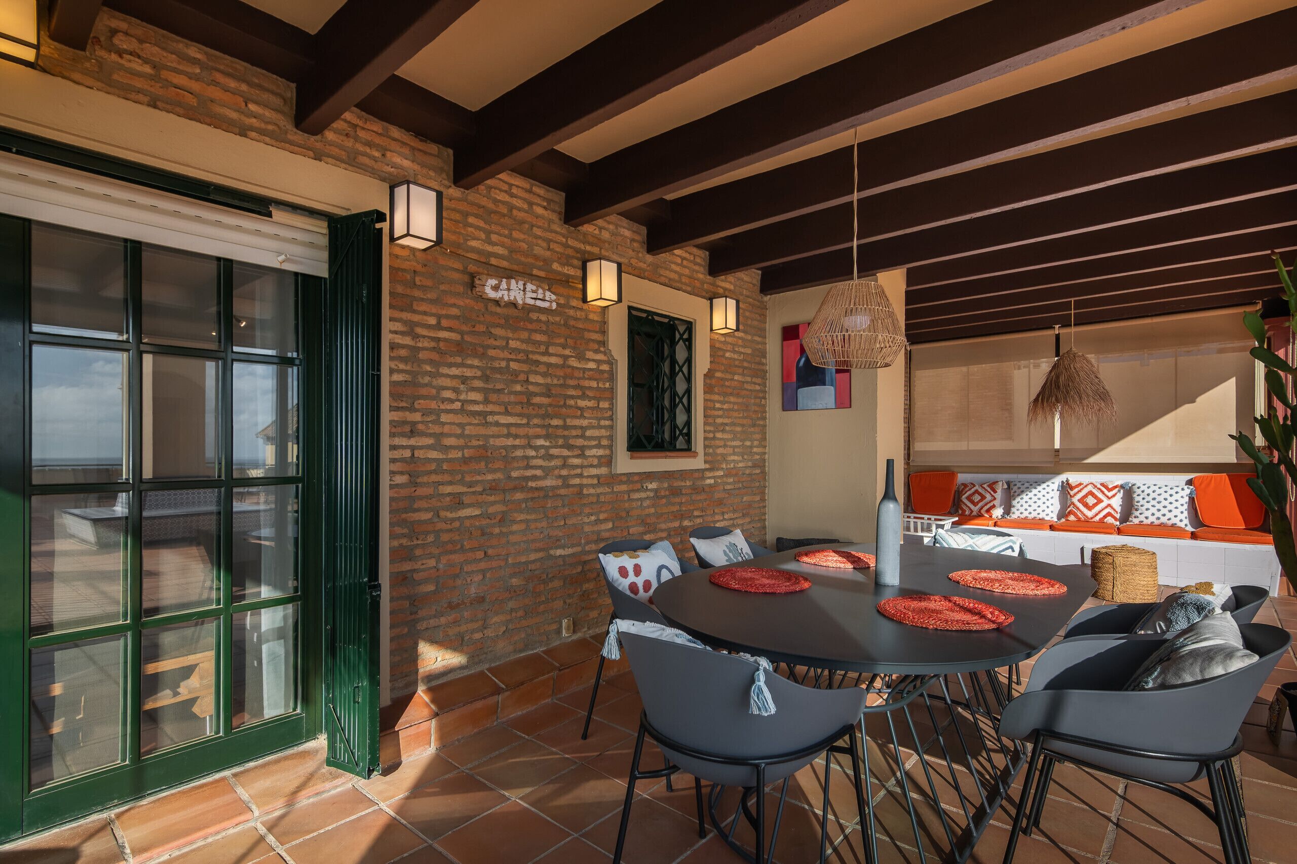 A dining area with a brick wall, a large window, and a table with chairs.