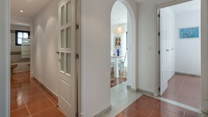 A hallway with white walls, a tiled floor, and a door leading to a dining area. - Alcaudon - Playa Isla Canela IACL95P35 (Isla Canela)